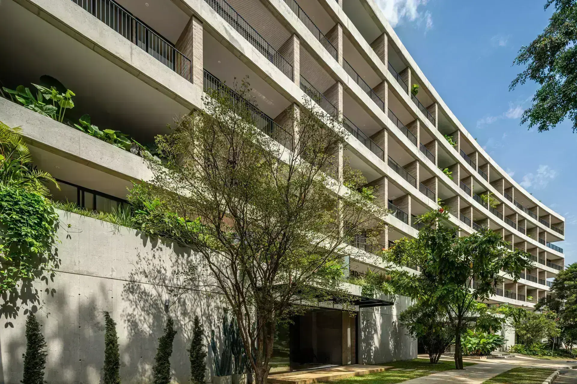 Fachada del Edificio Residencial C42 en Medellín por Obra Negra Arquitectos. Concreto expuesto y balcones verdes.